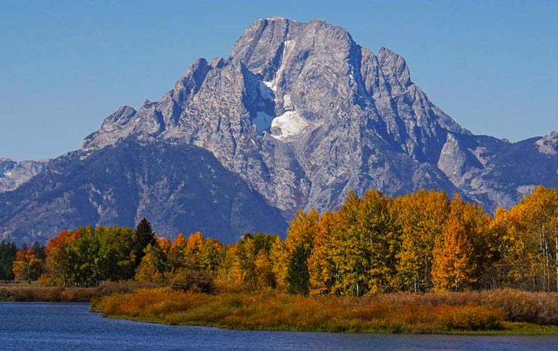 Mt Moran as seen at Oxbow Bend at Grand Teton National Park. Trees in foreground have turned fall colors. Photo credit: j. bonney @ nps.gov - date taken: 9/26/2021