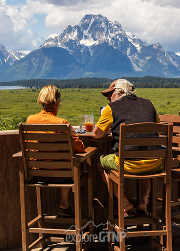 Woman and man having drinks at a table overlooking Mt. Moran in Grand Teton National Park